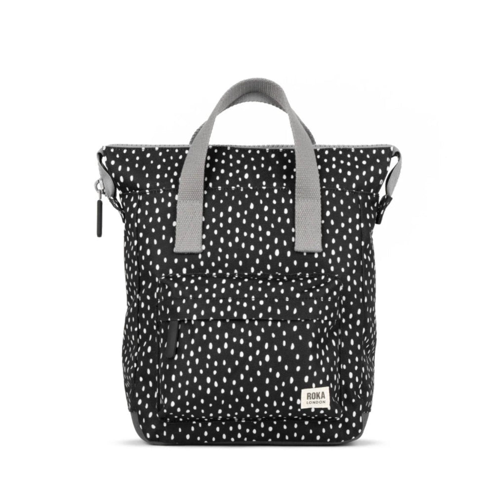 A small Roka Bantry B recycled canvas backpack with a blue geometric pattern, featuring a front pocket, two side handles and a vegan pull zipper.