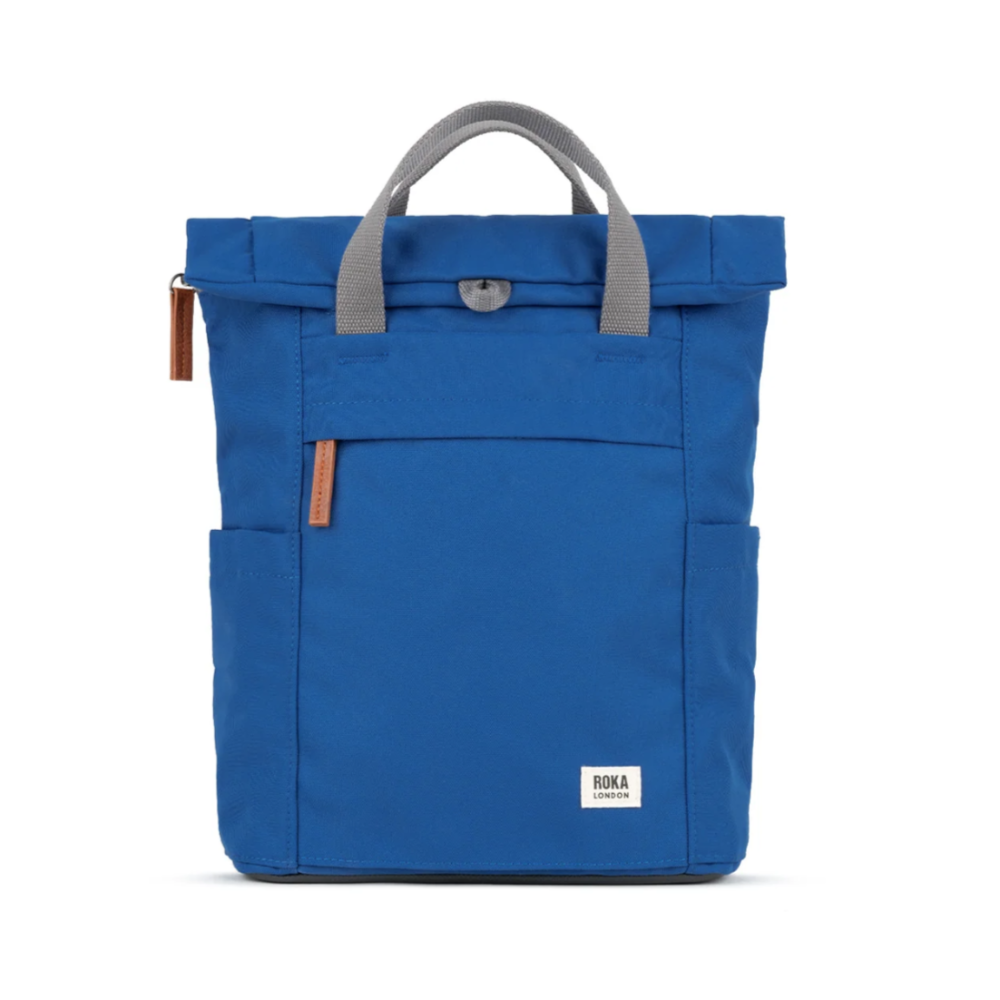 A blue Roka Finchley A small recycled canvas backpack with two handles, a front pocket, and a zipper closure.