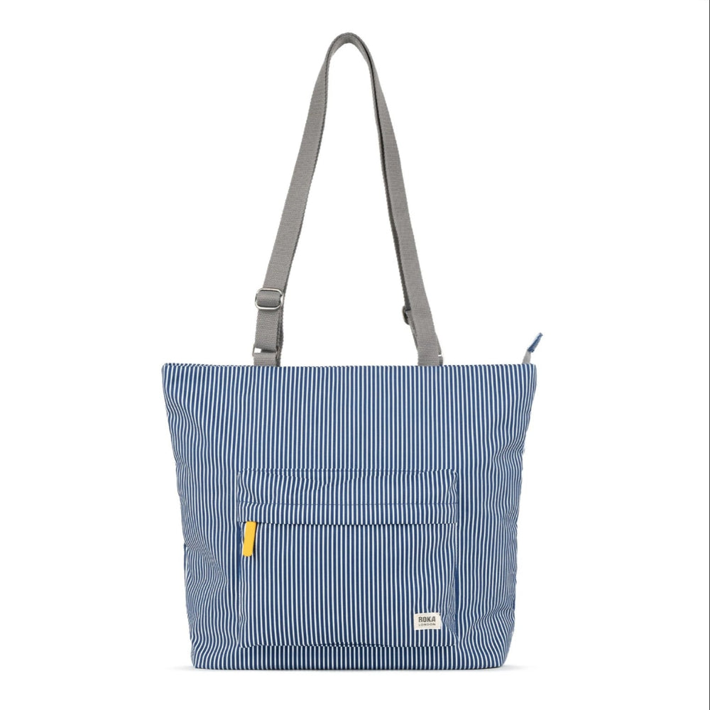 A medium-sized blue striped tote bag with adjustable grey straps and a front pocket, made from recycled canvas.