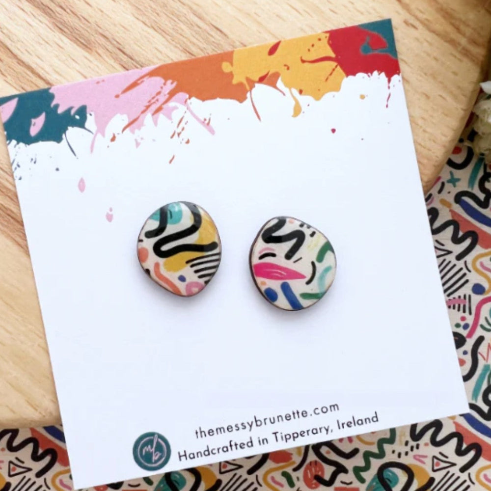 Colorful abstract patterned earrings on a branded card with a colorful background