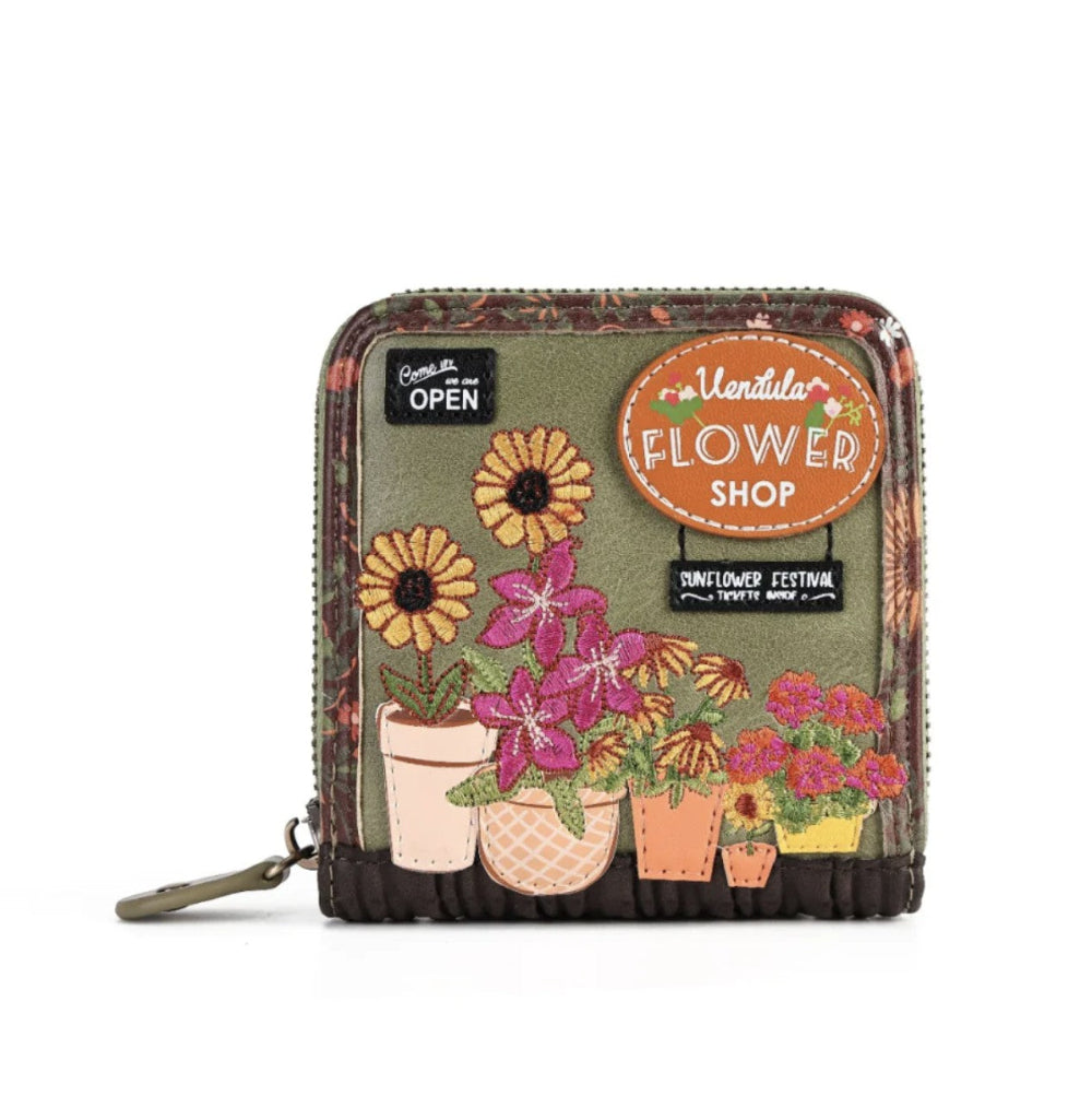 A small zip-around wallet with a floral patchwork design, featuring embroidered potted flowers and decorative signs that read 'Vendula Flower Shop' and 'Sunflower Festival'.