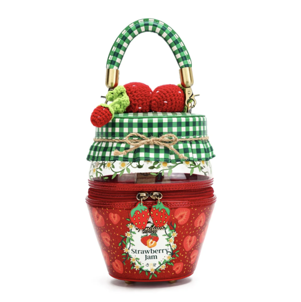 A strawberry jam-themed handbag designed to look like a glass jar of strawberry jam, featuring a red body with strawberry patterns, a green and white gingham handle, and decorative crochet strawberries on top.