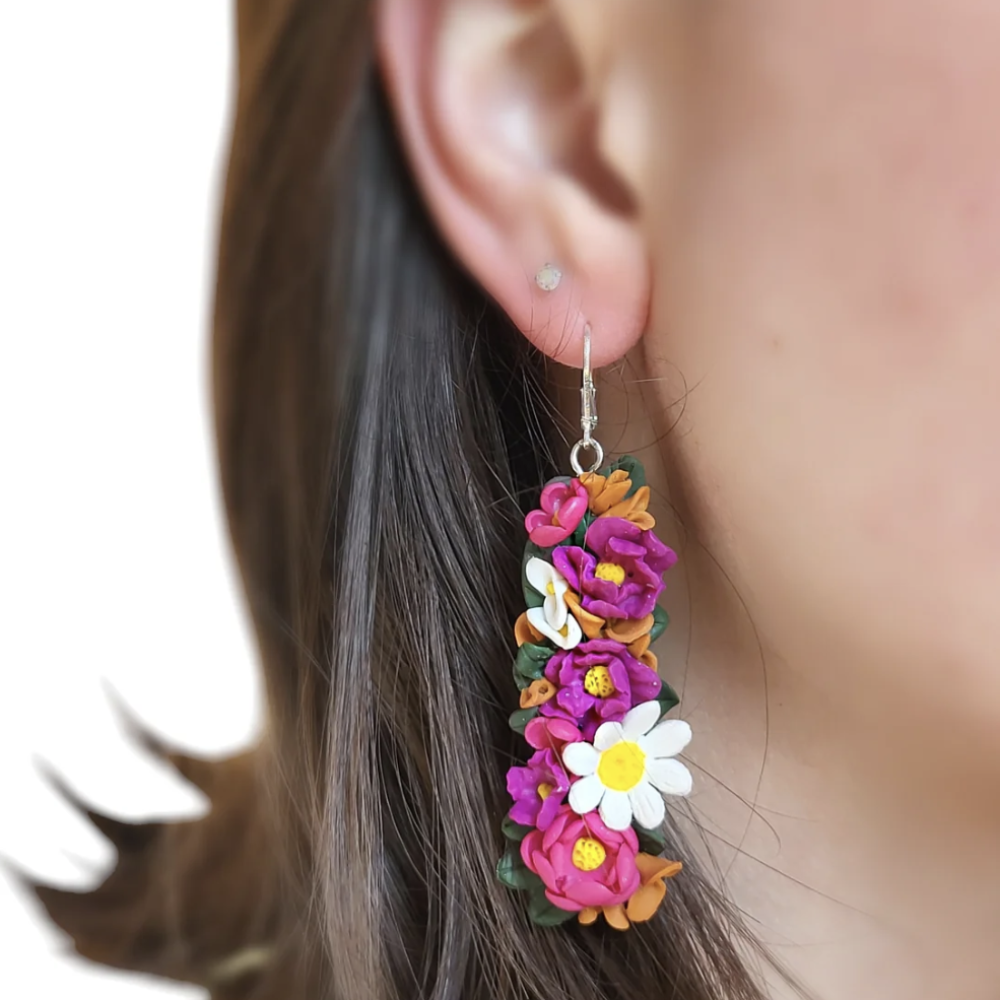 Close-up of a person wearing colorful floral earrings with a blurred background