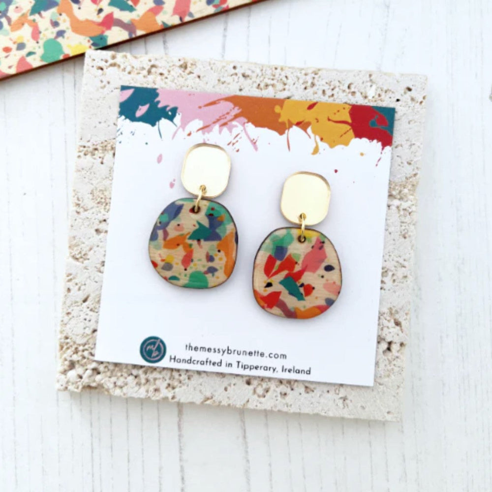 Colorful earrings on a branded card with a colorful background