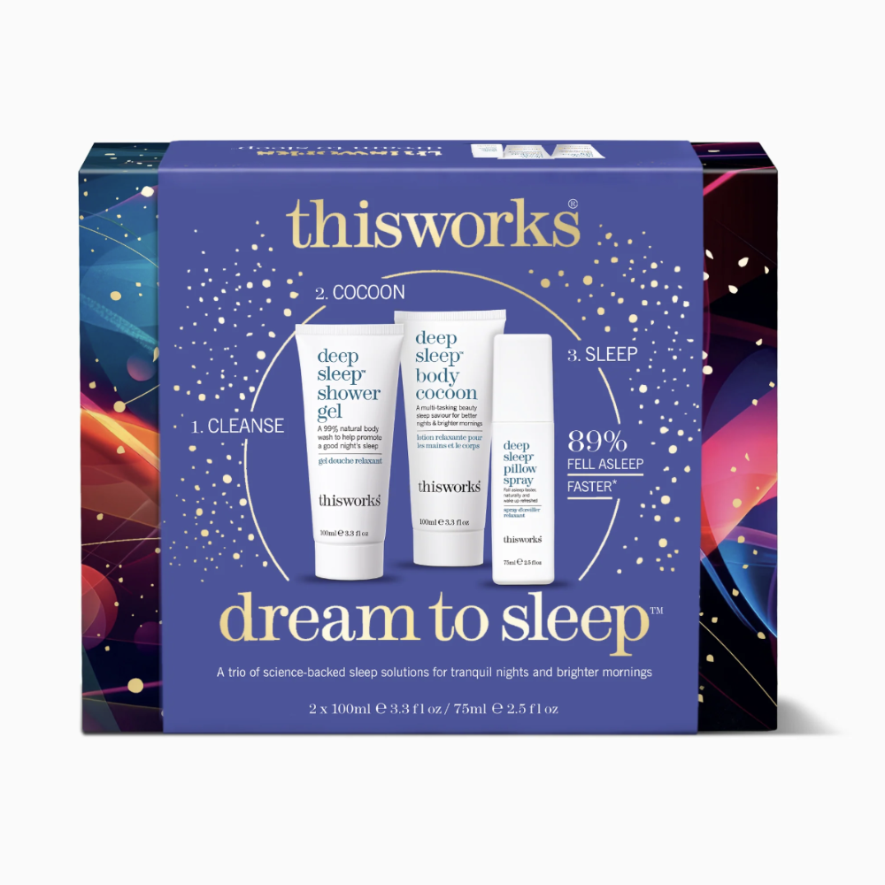 Thisworks Dream to Sleep gift set box featuring three skincare tubes (deep sleep shower gel, deep sleep body cream, and deep sleep sleep aid) on a dark blue background with colorful cosmic illustrations on the side panels.
