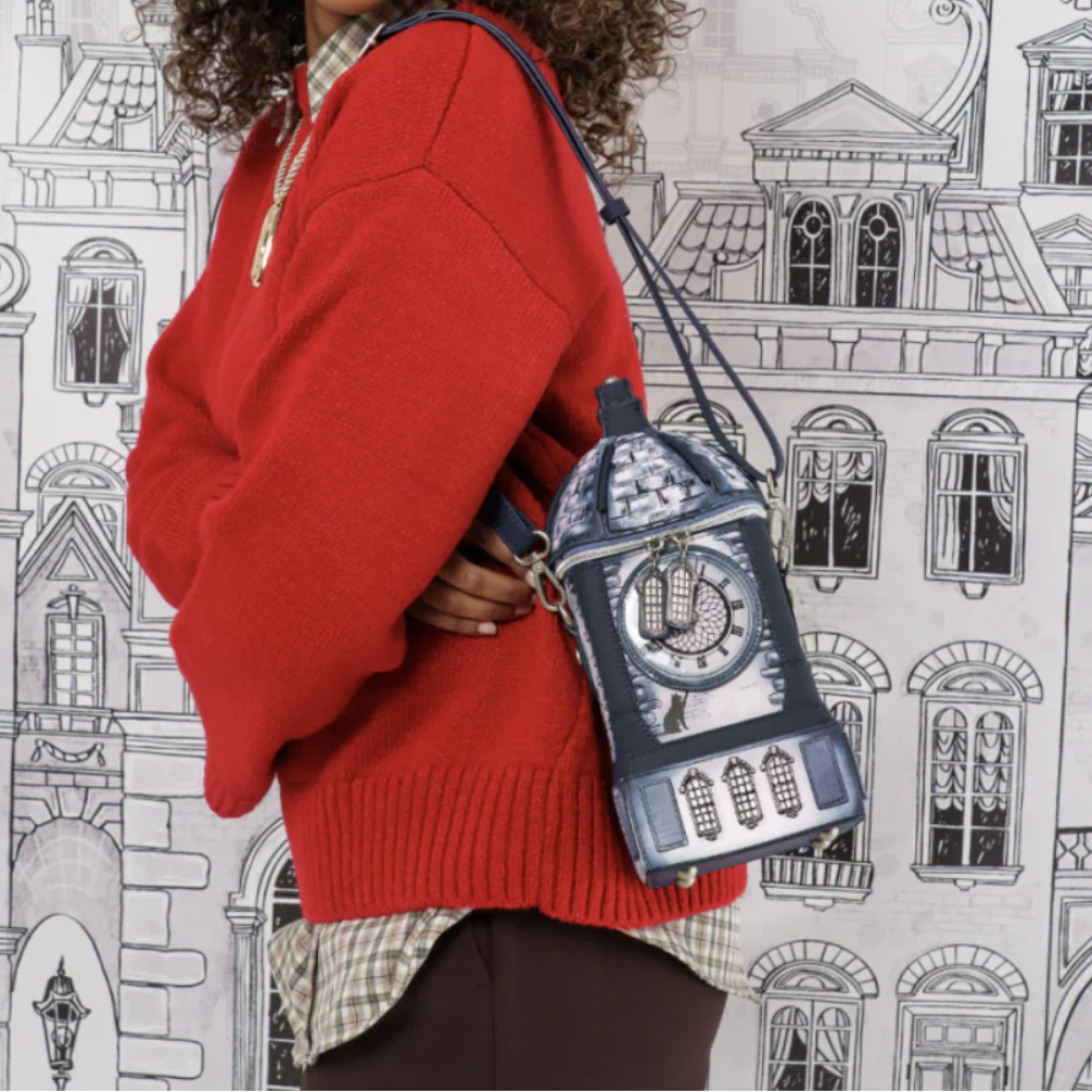 A person wearing a red knit sweater and a checkered shirt carries a small dark blue and silver clock-shaped shoulder bag against a black-and-white illustrated city building background.