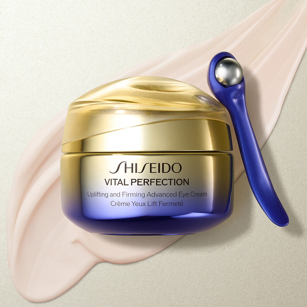 Shiseido Vital Perfection eye cream with applicator on a beige background