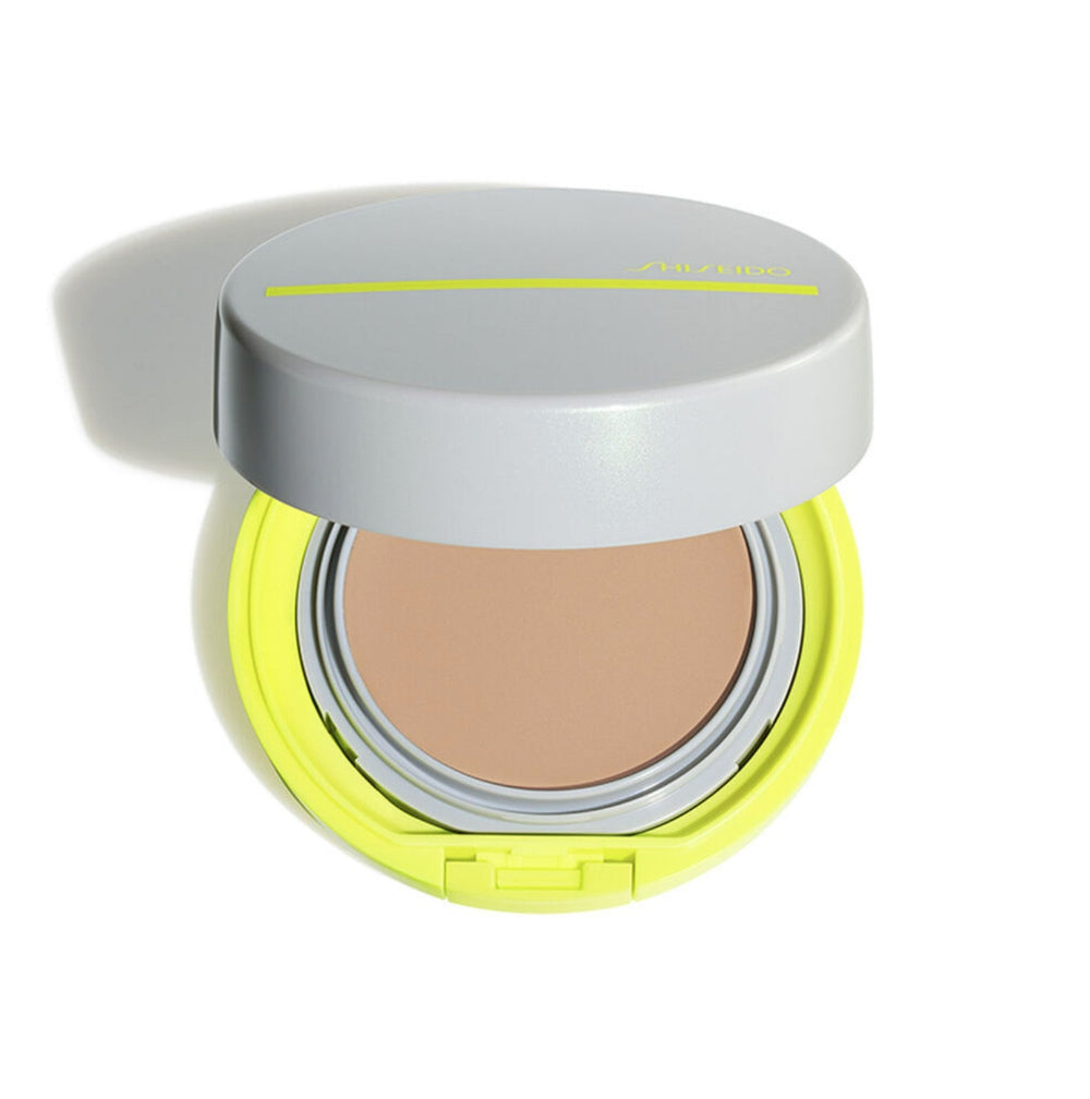 Compact powder with a yellow case and silver lid on a white background