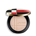 Shiseido color + enahncer Pressed Powder compact shown open, featuring a black circular case with a gold rim and a lid decorated in a red, black, white, and beige checkered pattern. The pressed powder inside is a light, shimmery peach-beige with the Shiseido logo embossed in the center.
