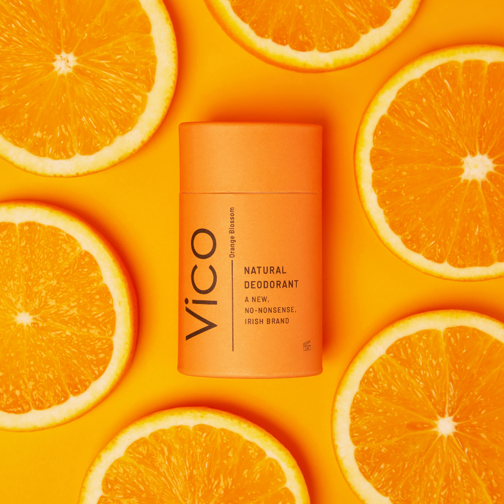Vico natural deodorant stick on a bright orange background with orange slices
