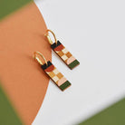 Colorful checkered earrings on a white surface with a brown and green background