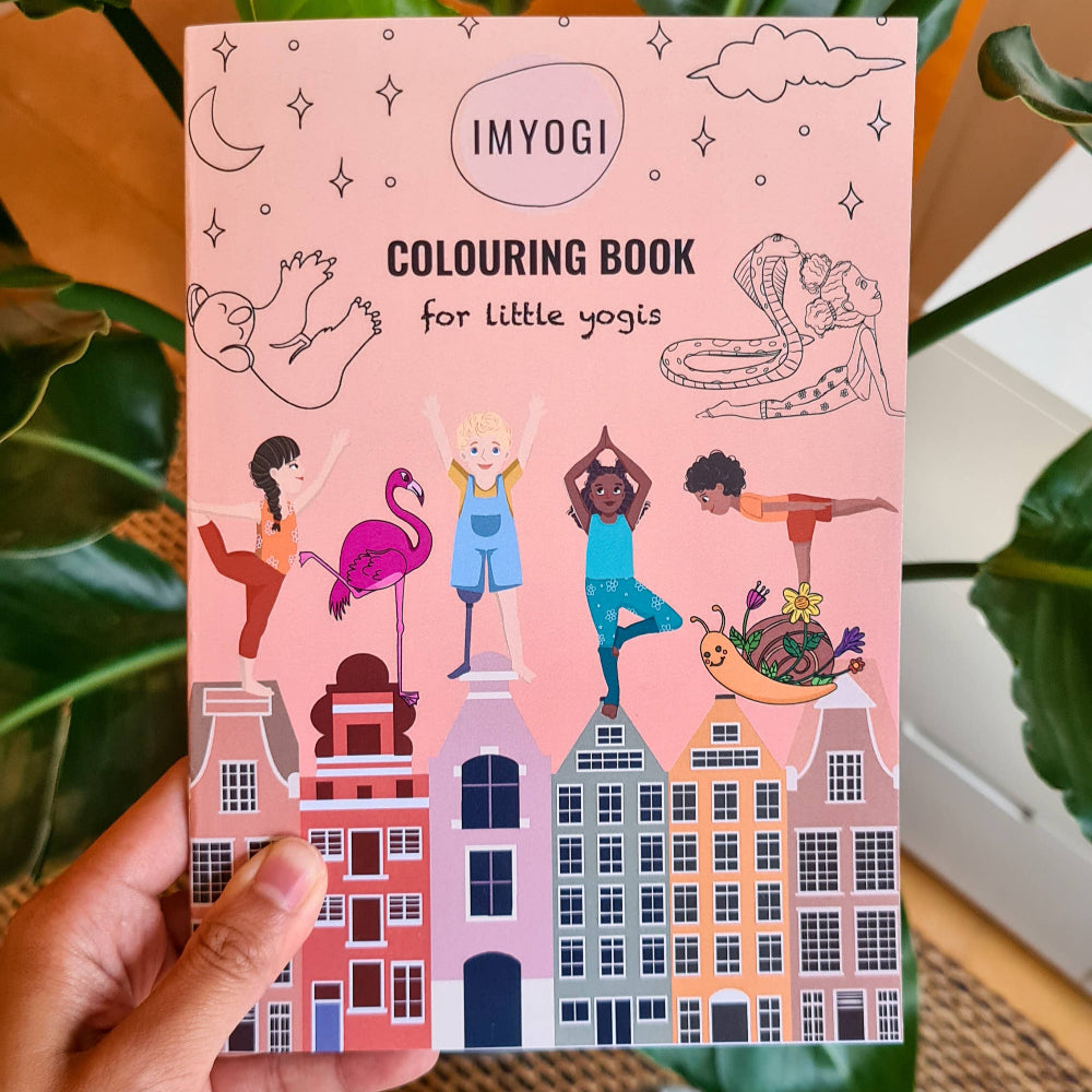 Pink coloring book titled 'IMYOGI' held by a hand with green foliage in the background