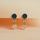 Pair of earrings with blue, gold, and pink circular designs on a two-tone background.