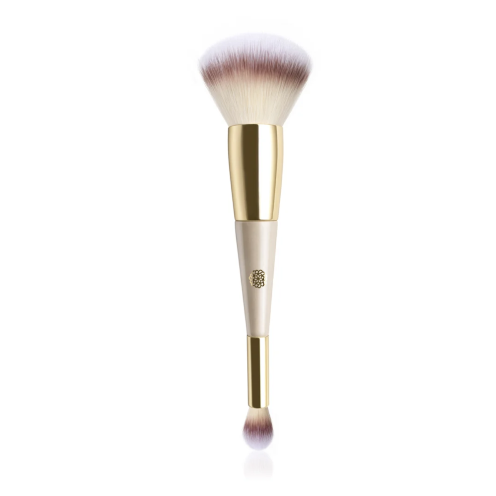 A dual-ended makeup brush with a large fluffy brush on top and a smaller angled brush at the bottom, featuring a cream-colored handle, gold ferrule, and soft white-to-rose bristles, shown on a white background.