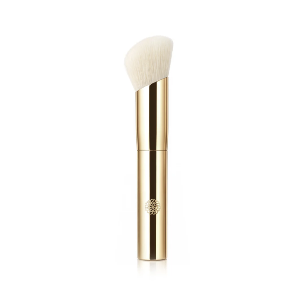 A gold makeup brush with a rounded triangular white bristle head, shown vertically on a clean white background.