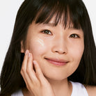 Close-up of a person with a neutral expression, touching their cheek.