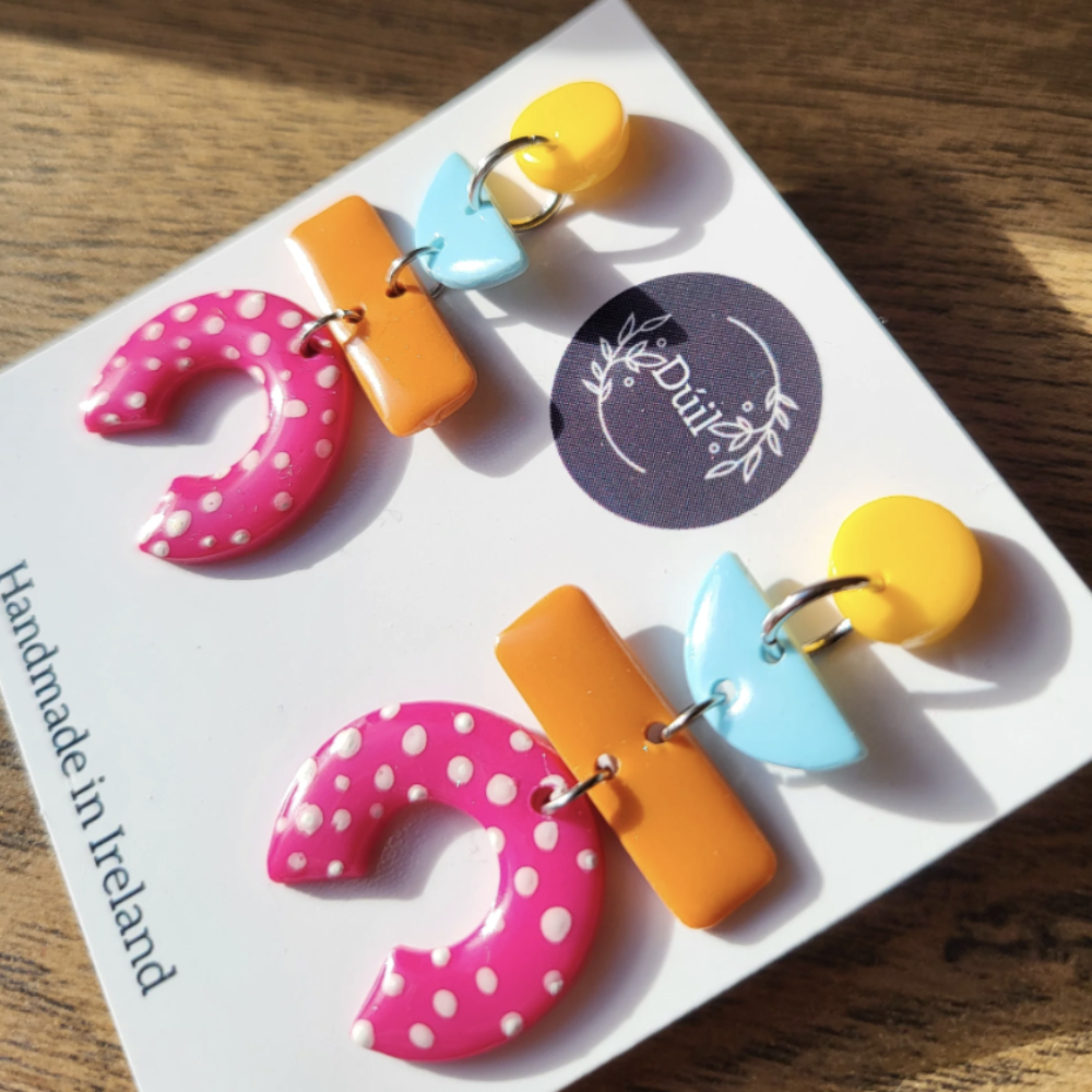 Colorful earrings on a white card with 'Duil' branding.