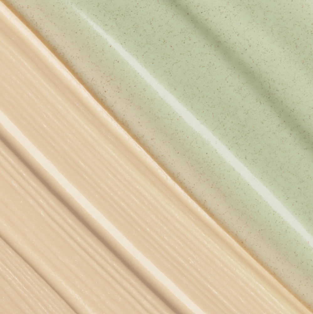A close-up texture shot showing two cream-colored cosmetic swatches with fine speckles, divided diagonally with a white highlight.