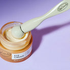 Eye cream jar with a applicator on a purple background