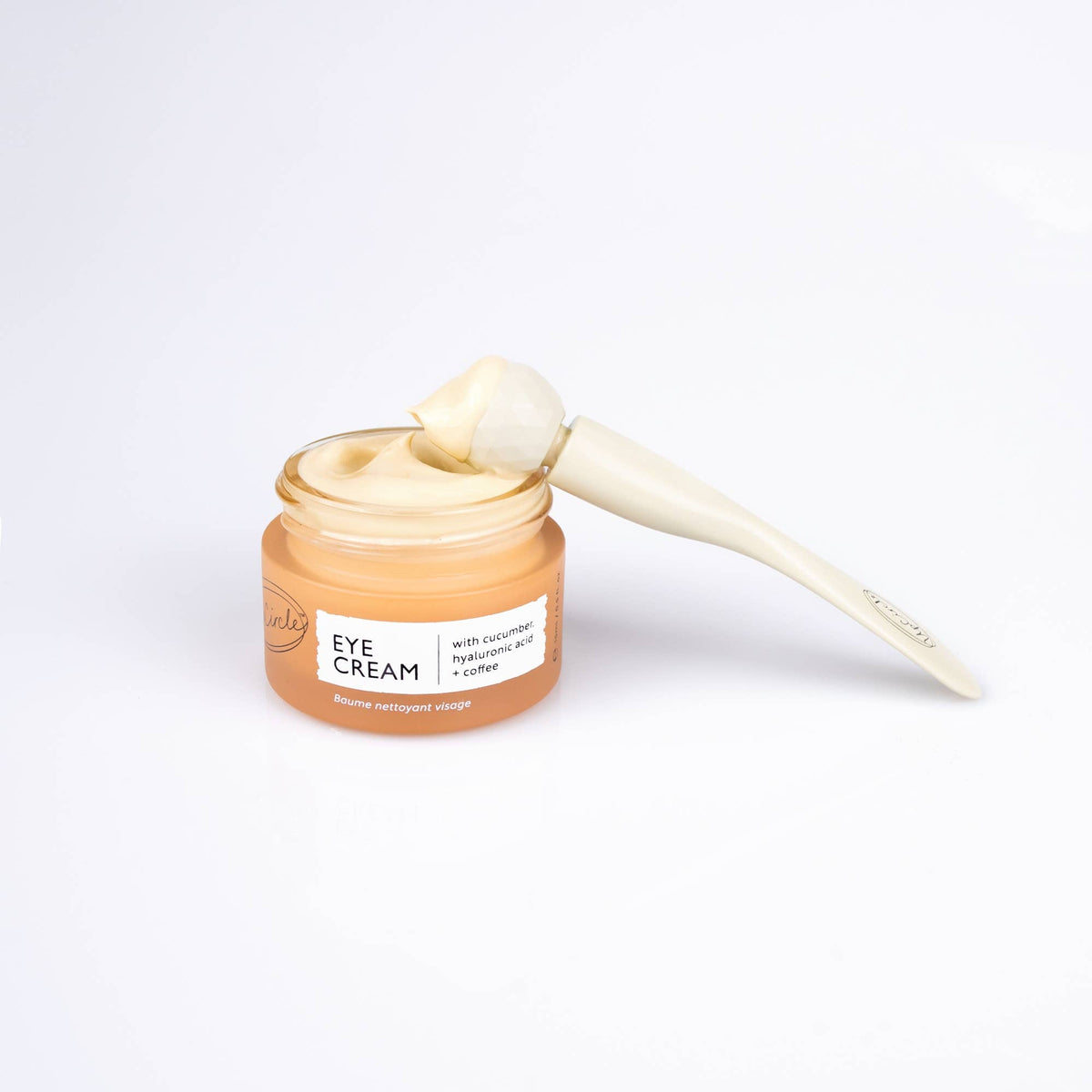 Jar of eye cream with a applicator on a white background