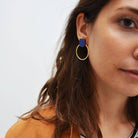 Close-up of a person wearing a blue hoop earring with a plain background