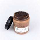 Jar of face scrub with a black lid on a white background