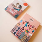 Two books with illustrated covers on a light beige background