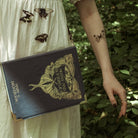 Blue book-shaped handbag with butterfly design and 'Moths and Butterflies' text 