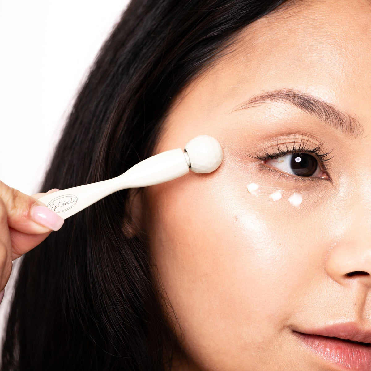 Person applying cream to face with a eye roller