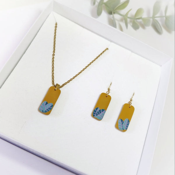 Gold necklace and earrings with blue leaf designs on a white background