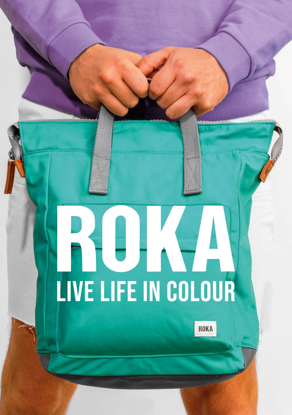 Person holding teal Roka backpack bag
