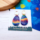 Colorful teardrop earrings on a branded card with a colorful background