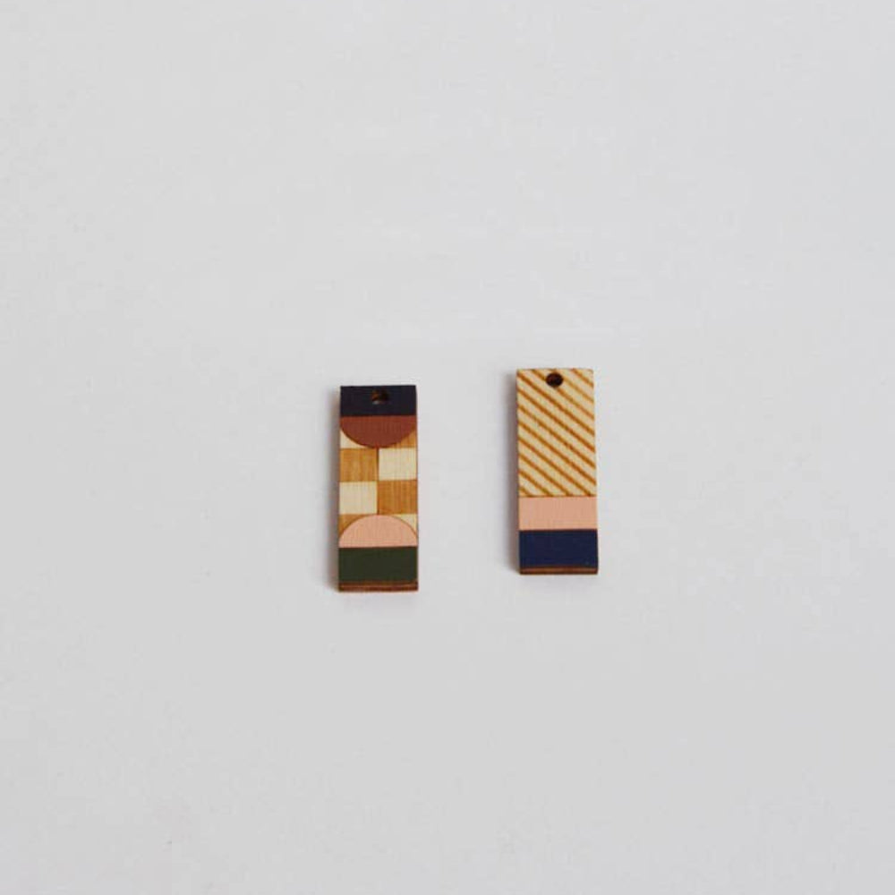 Two geometrically patterned earrings on a light gray background