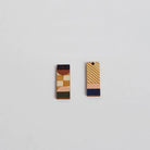 Two geometrically patterned earrings on a light gray background