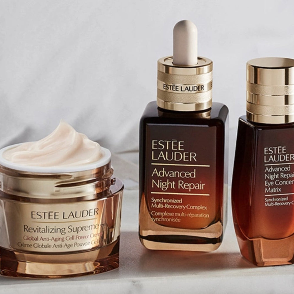 Estée Lauder skincare products including a jar, dropper bottle, and serum on a light background