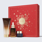 Estée Lauder holiday gift set featuring a red gift box with gold snowflake patterns and three skincare products in front: a brown and gold Advanced Cleansing Gel tube, a dark brown Advanced Night Repair Serum dropper bottle, and a dark blue Revitalizing Supreme cream jar.