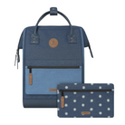 A blue and navy backpack with a matching zip pouch featuring a white daisy pattern, displayed on a clean off-white background. Both items have brown leather accents and a circular logo patch on the front.