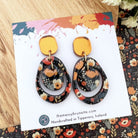 Pair of floral earrings on a branded card with a floral patterned background