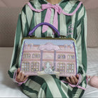 Woman holding a decorative handbag in a bedroom setting with a pink phone on the bed.