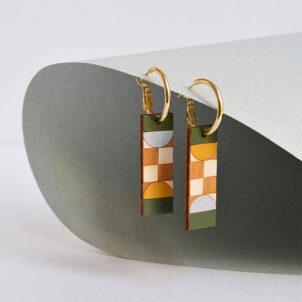 Geometric earrings on a stone surface with a neutral background