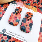 Colorful abstract-patterned earrings on a branded card with a colorful background