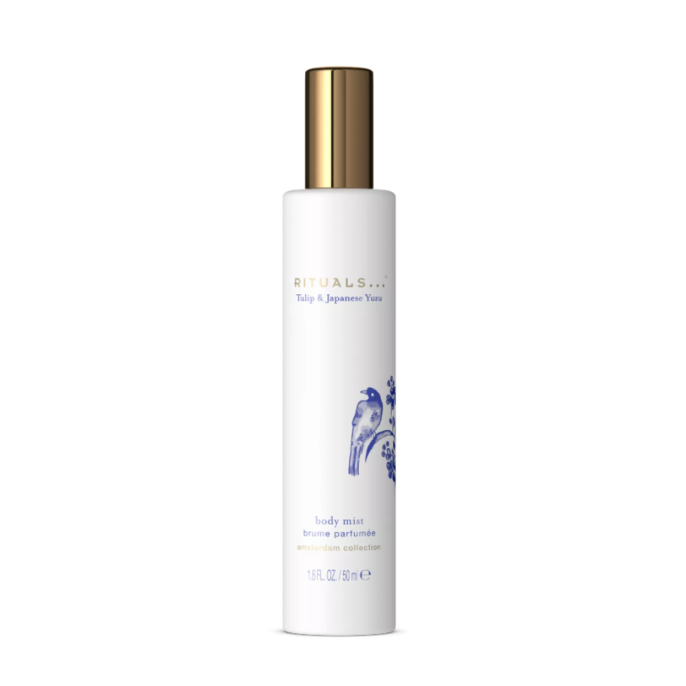 A tall white cylindrical bottle of RITUALS body mist with a metallic gold cap, featuring blue and gold text and a blue illustration on a clean white background.