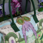 Handbag with garden design and green handles, featuring a brand tag.