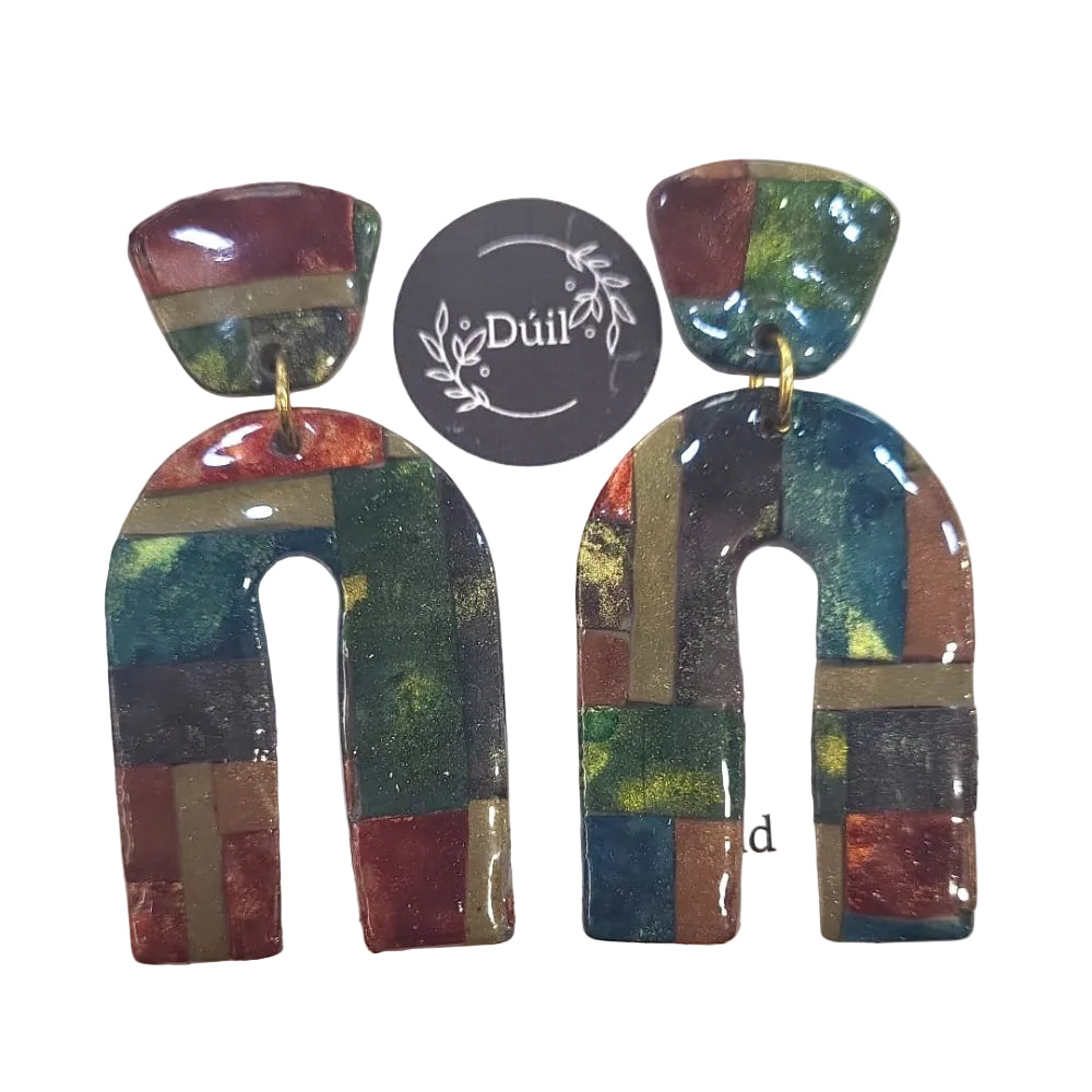 Pair of colorful abstract earrings on a white background with 'Duil' branding.