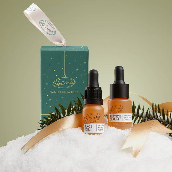 UpCircle skincare products including face oil and serum with packaging on a white and green background.