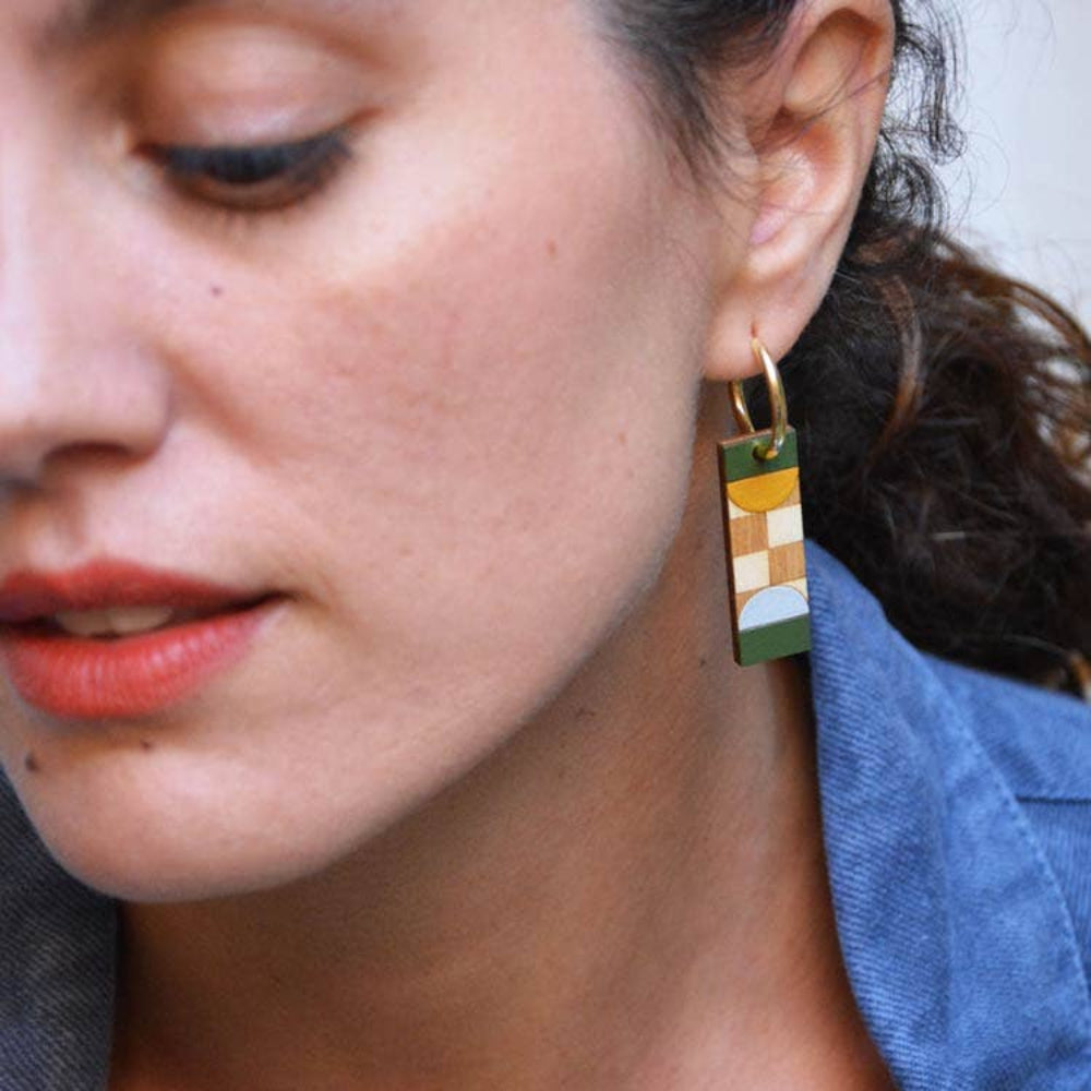 Close-up of a person wearing a colorful geometric earring with a blue shirt.
