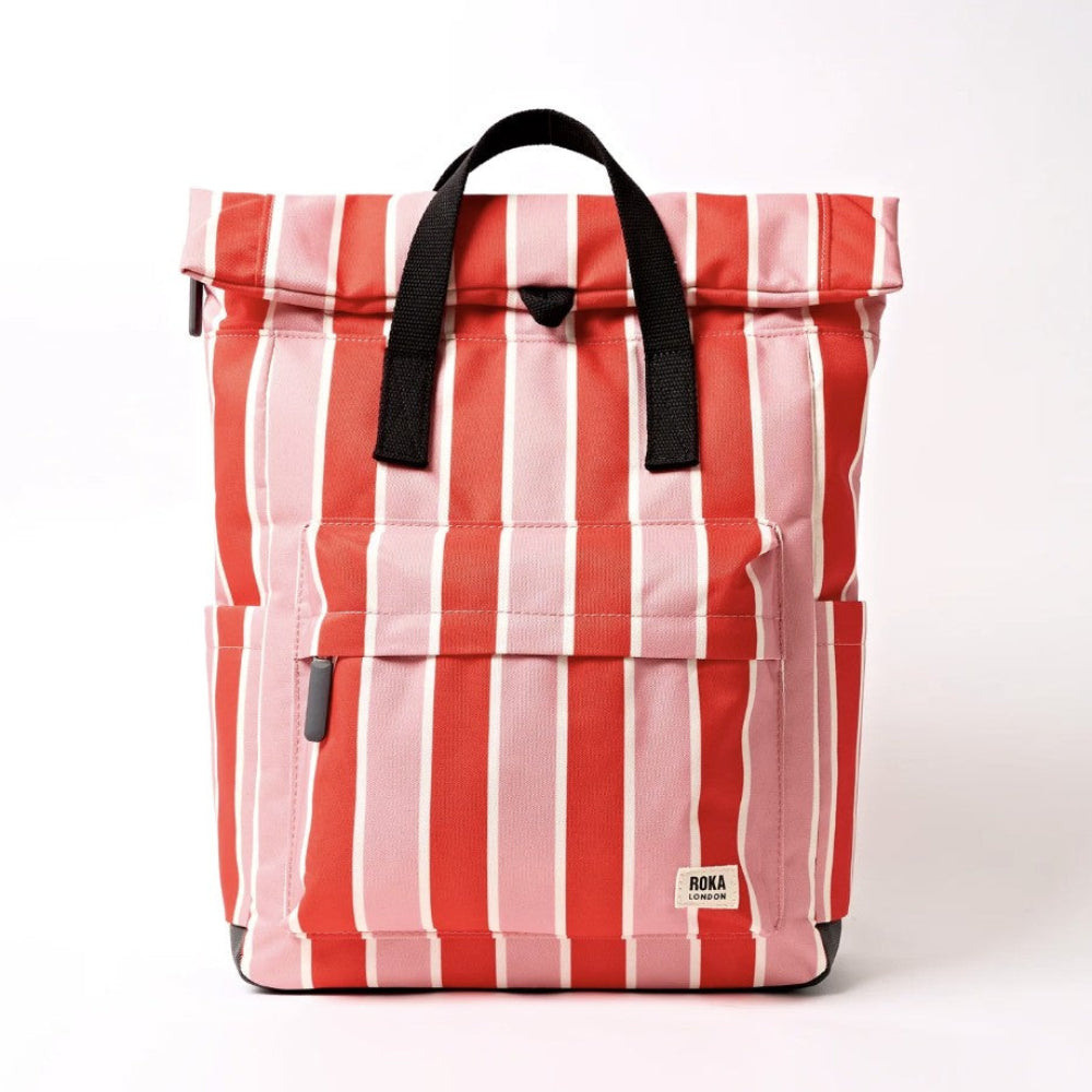 A roll-top backpack with vertical red, pink, and white stripes, featuring black webbed top handles