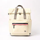 A cream-colored roll-top backpack with grey handles, a front zippered pocket featuring a pink stripe.