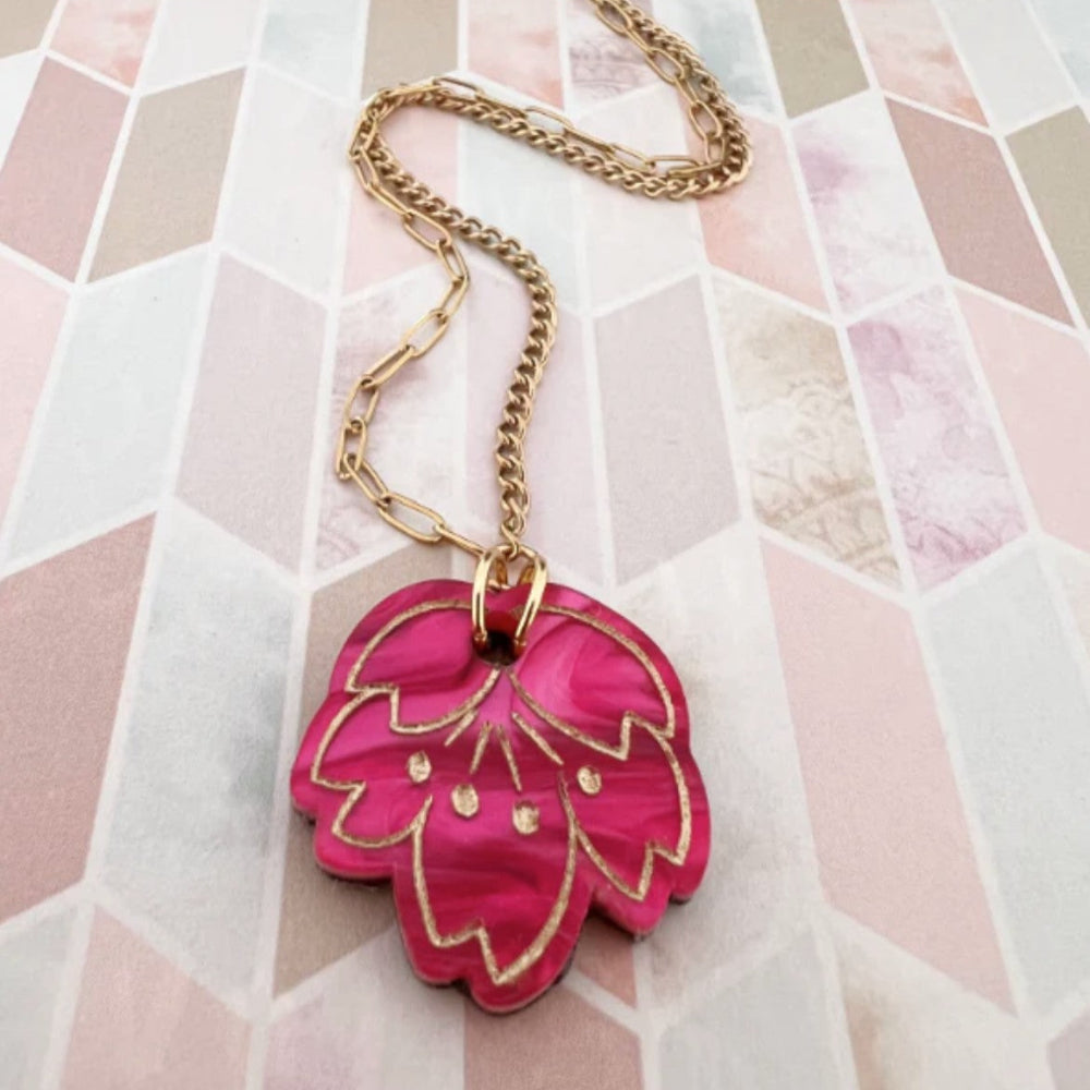 Necklace with a pink floral pendant on a patterned background