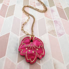 Necklace with a pink floral pendant on a patterned background